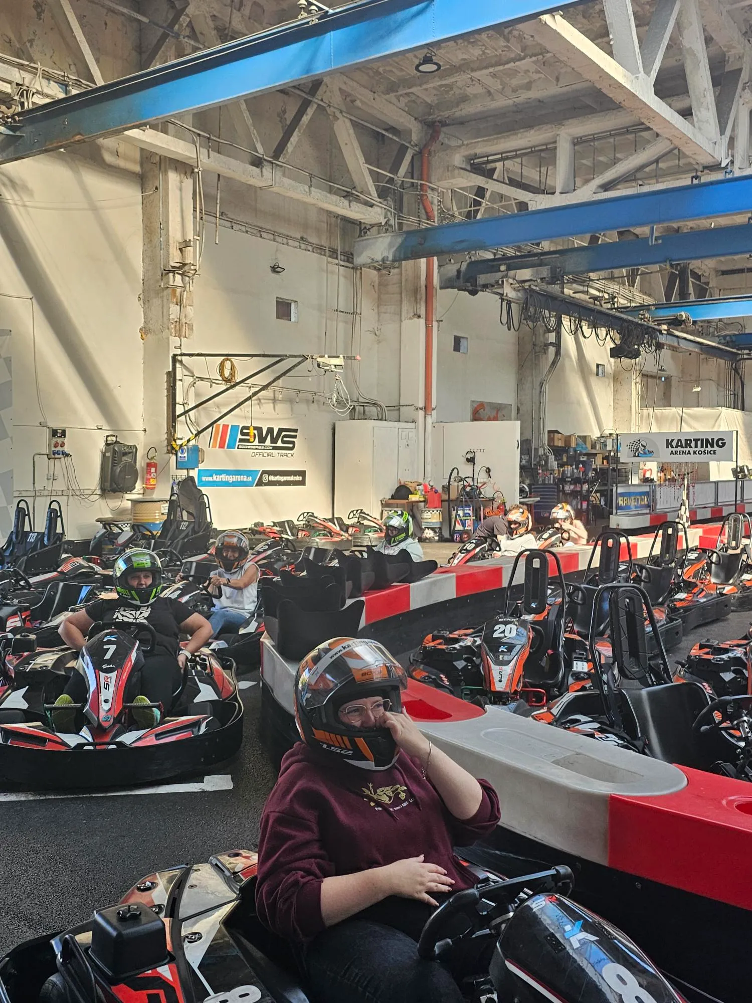 Motokáry pripravené v boxoch Karting arény a kolega v motokáre